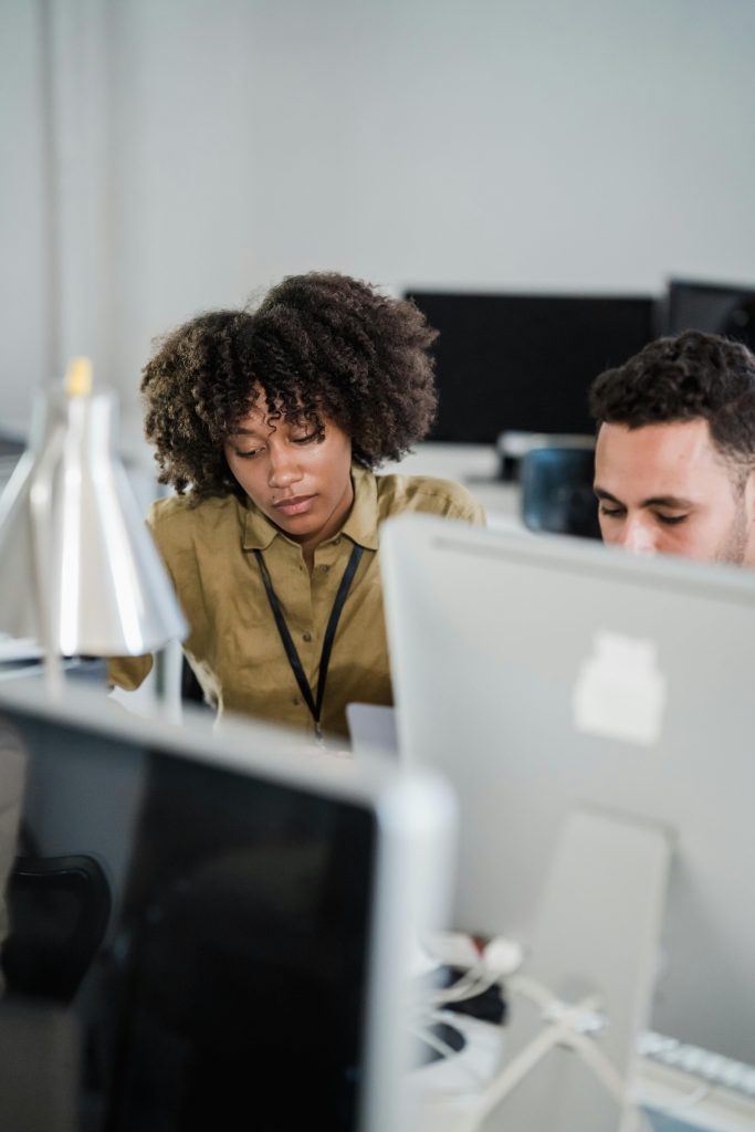 Two colleagues work together in a modern office setting, focusing on a project.