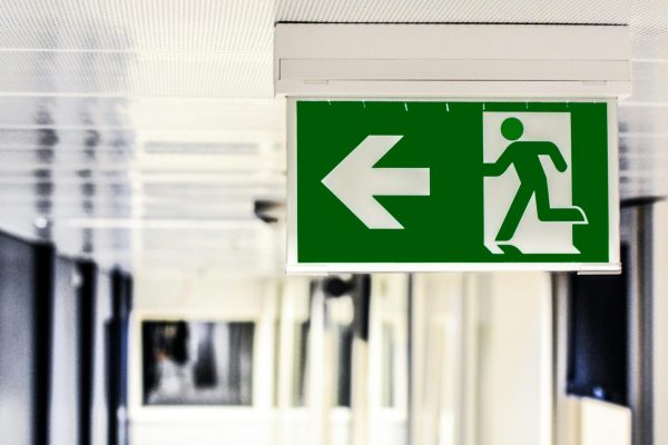 Green emergency exit sign with directional arrow in a hallway.